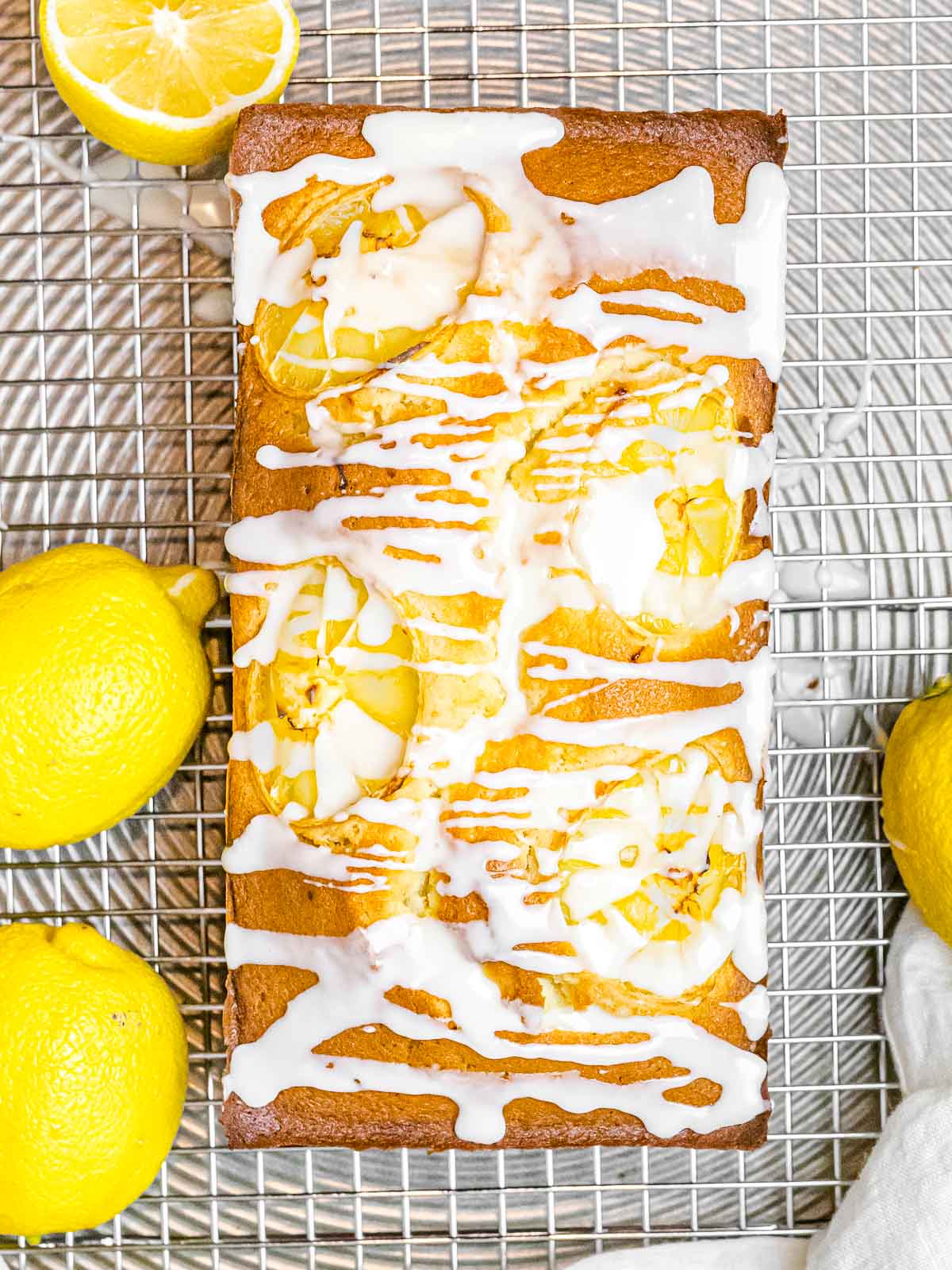 glazed lemon pound cake with white icing drizzled on top with lemons on the side
