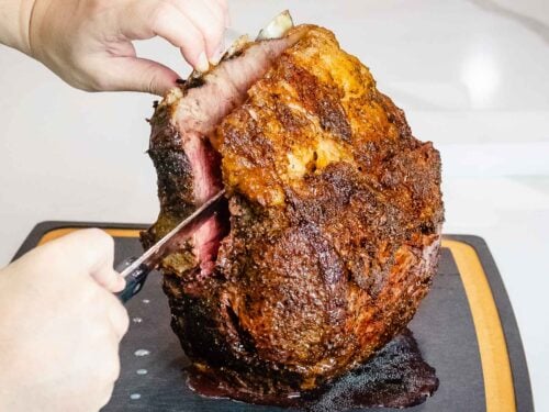 Standing rib roast with the rib bones being removed with a knife.