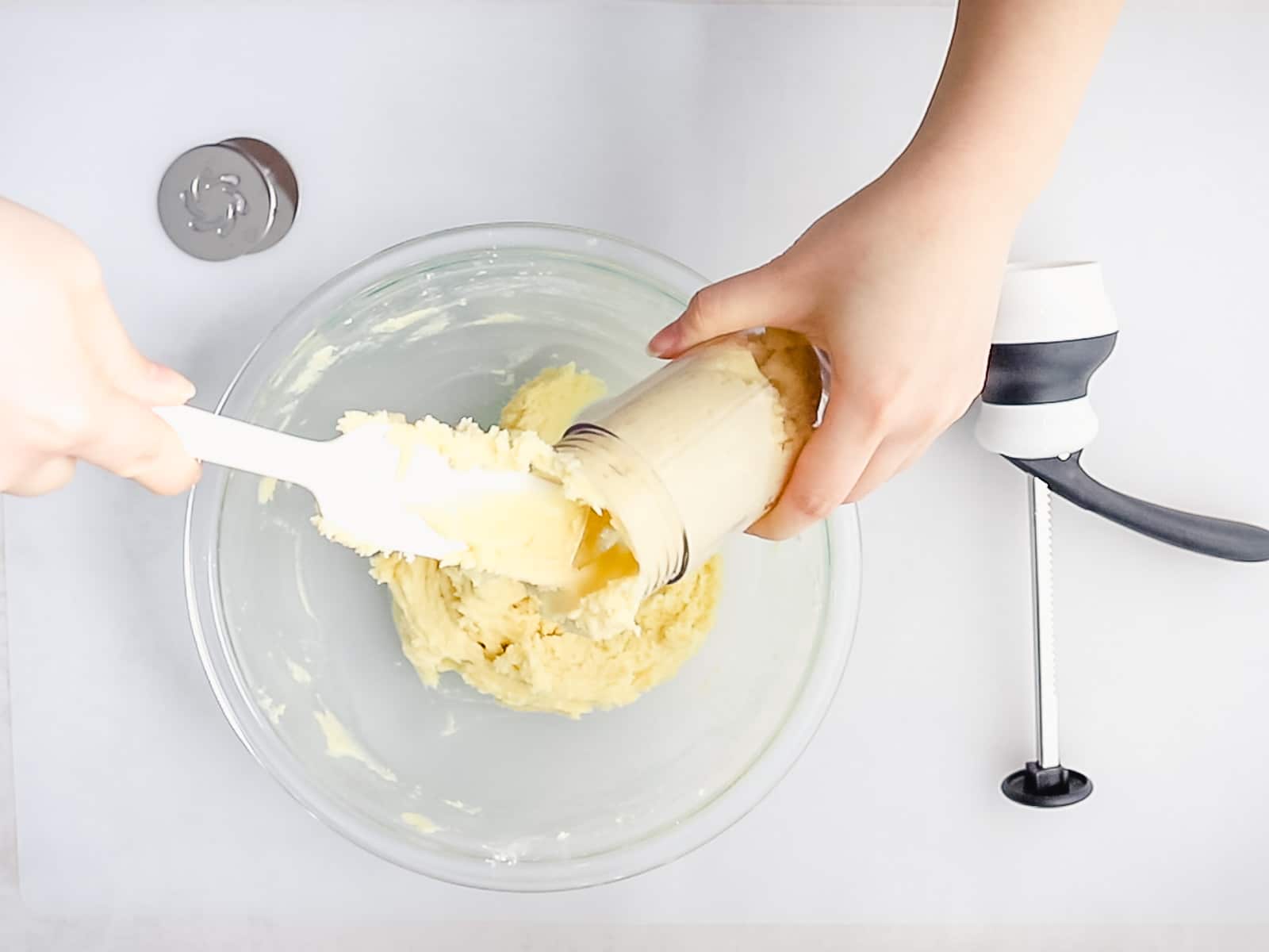 cookie dough batter being added to a cookie press with a white spatula