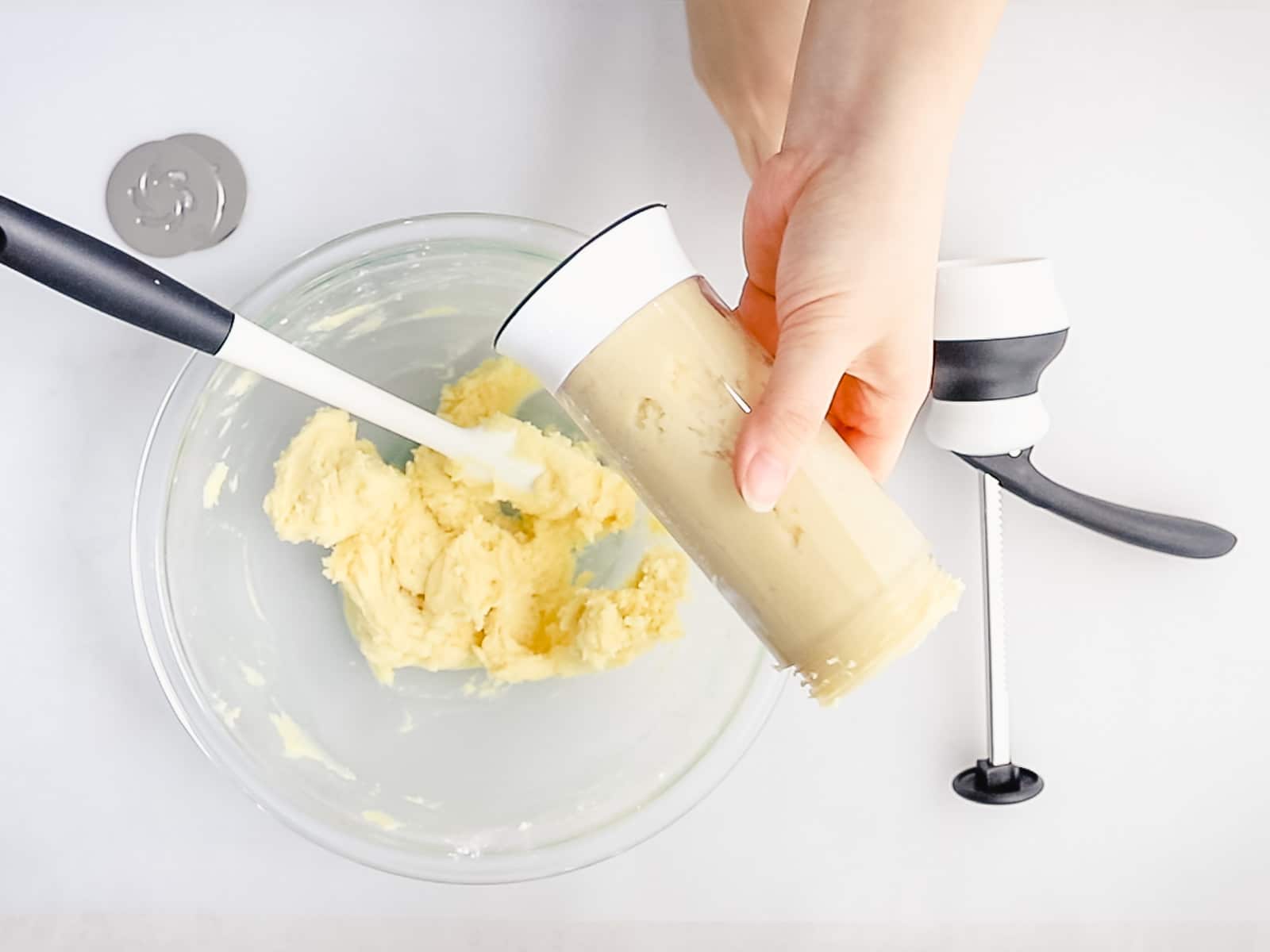 spritz cookie dough batter added to a spritz cookie press held by a hand