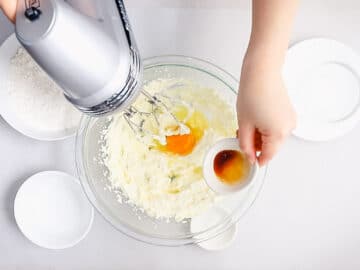 egg and vanilla added to creamed butter and sugar in a glass bowl with a hand mixer
