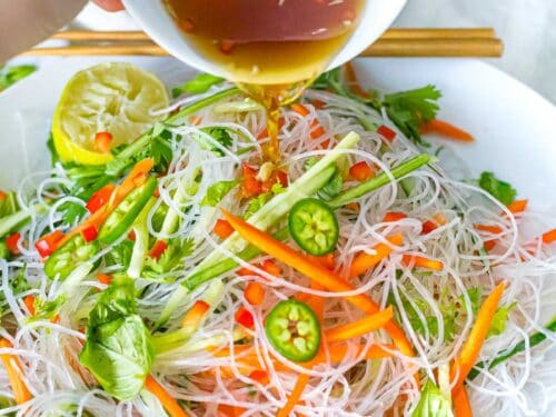 Cold Vietnamese rice noodle salad with dressing being poured on from a small white bowl.