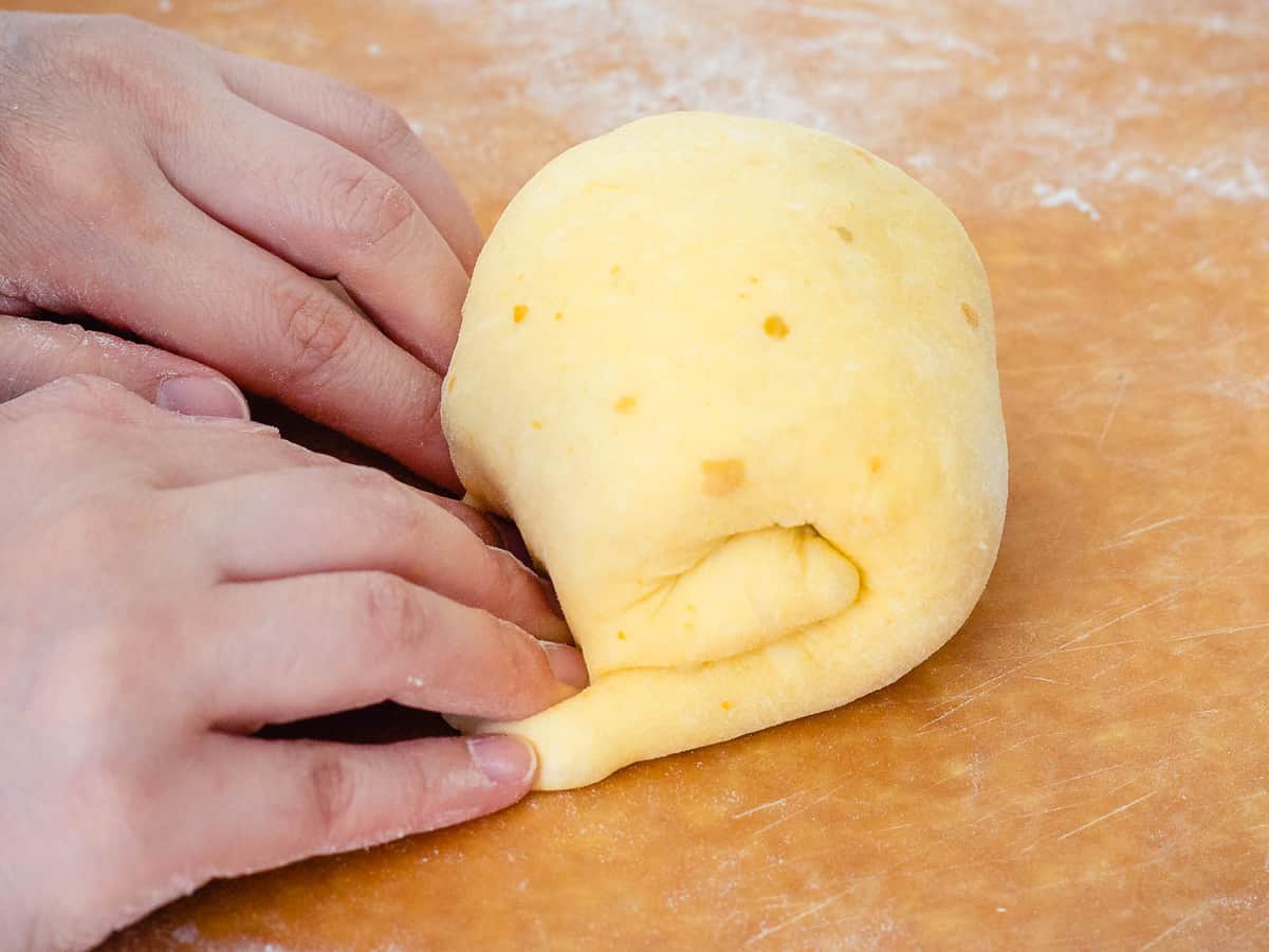 Hands rolling up the folded dough into a small round loaf.