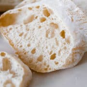 A loaf of ciabatta bread sliced open to reveal open crumb with large irregular holes.