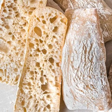 Sourdough ciabatta cut open to reveal large holes to show an open crumb with a crisp, crackly crust.