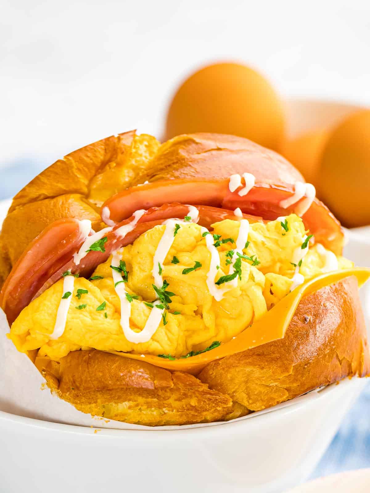 Breakfast egg sandwich inspired by Korean egg drop sandwich made with scrambled eggs, cheese, bacon, with mayo and parsley garnish.
