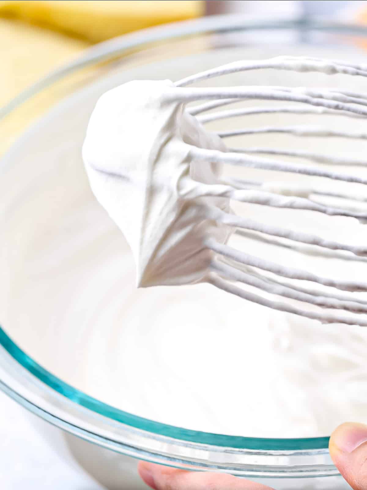 Close up of fluffy whipped cream on the end of a whisk.