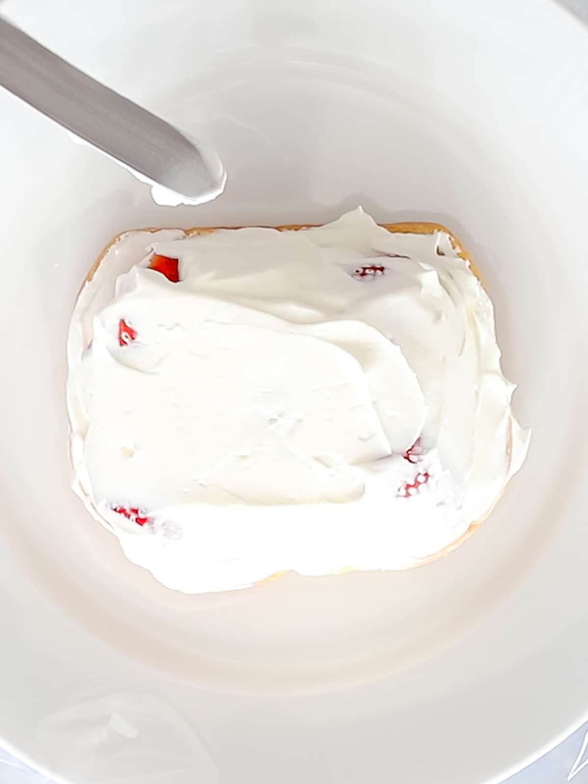 Fluffy whipped cream spread on top of strawberries and milk bread.