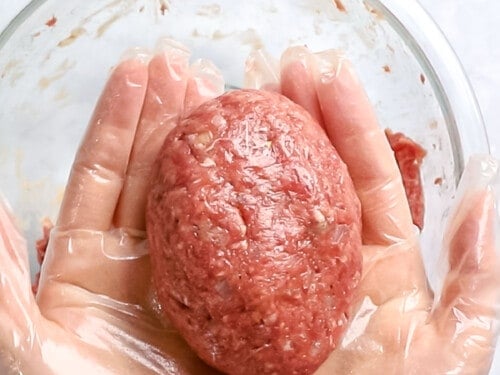 Hambagu patty of ground meat formed into a round oval shape and held in hands.