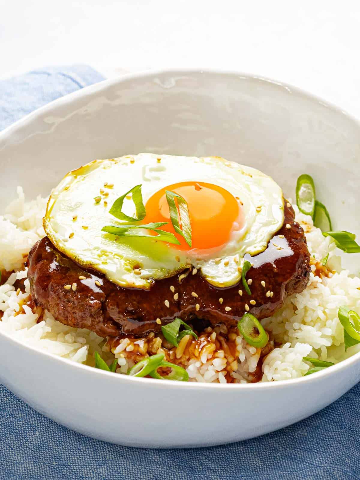 Loco moco made with a juicy burger, savory brown gravy, and a fried egg garnished with green onions.