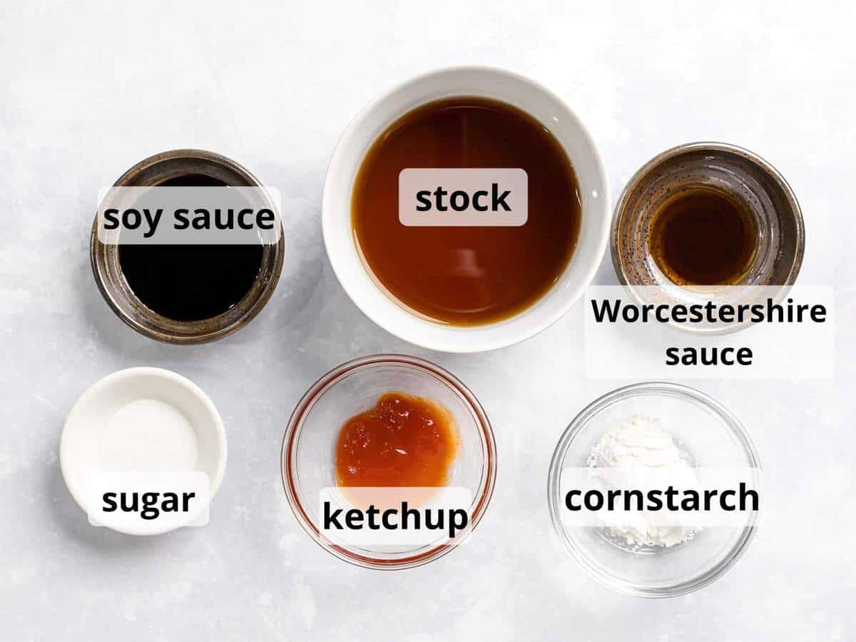 Ingredients for loco moco gravy in glass bowls including beef stock, cornstarch, soy sauce, and ketchup.
