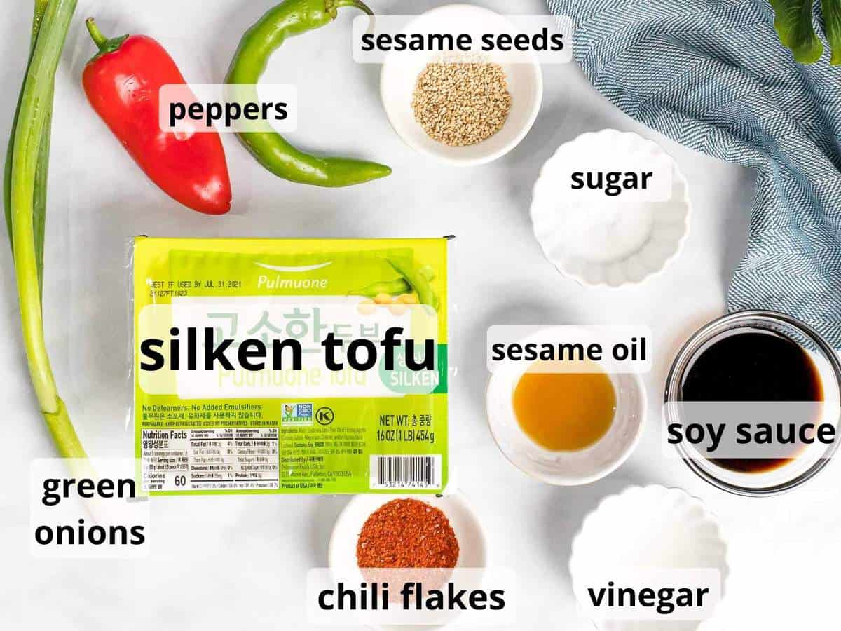 Ingredients for Korean silken tofu including soy sauce, green onions, and chili flakes in small bowls.