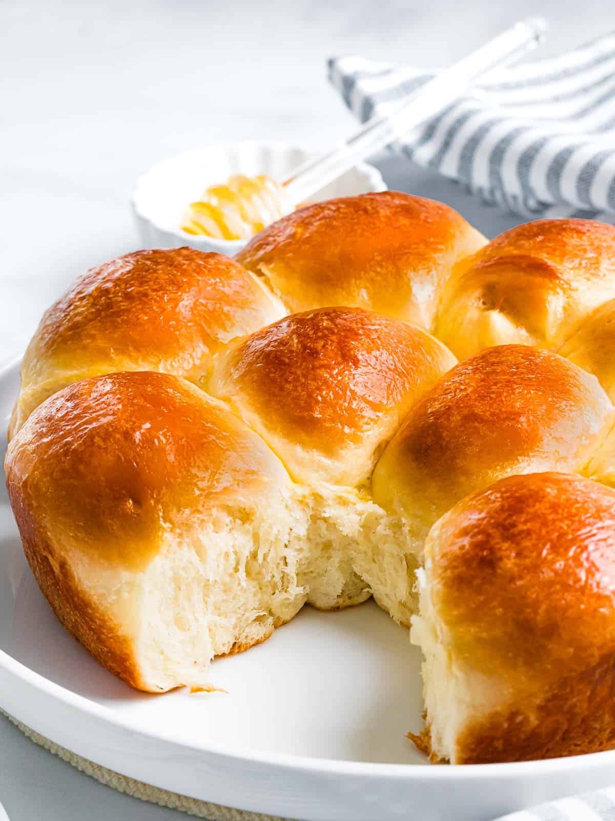 Soft and sweet brioche rolls with fluffy interior on a white plate.