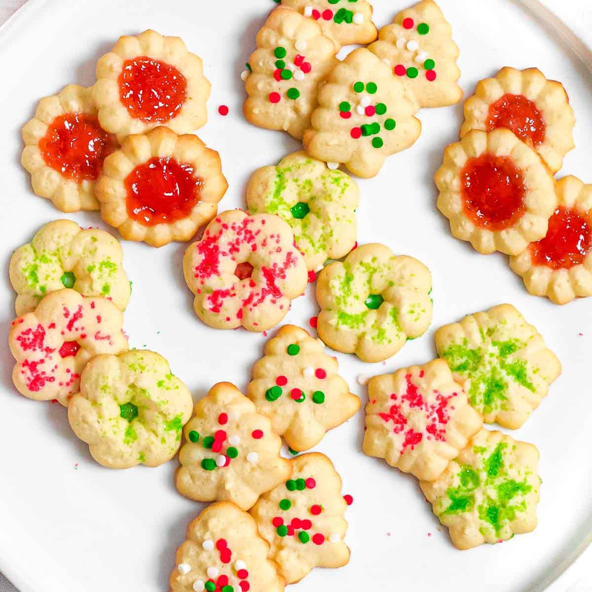 Christmas spritz cookies with red and green Christmas sprinkles on a plate.