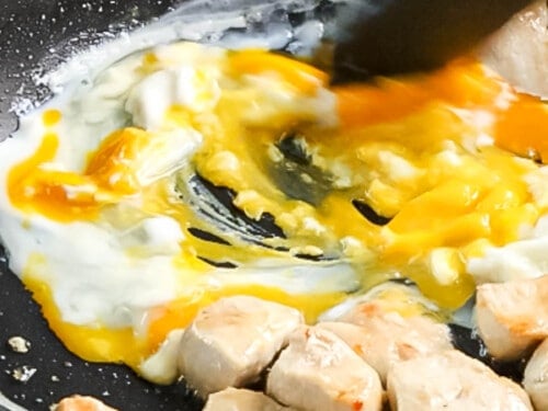 Frying and scrambling eggs in a pan with chicken.