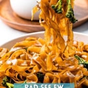 Pad see ew noodles held by chopsticks with text overlay.