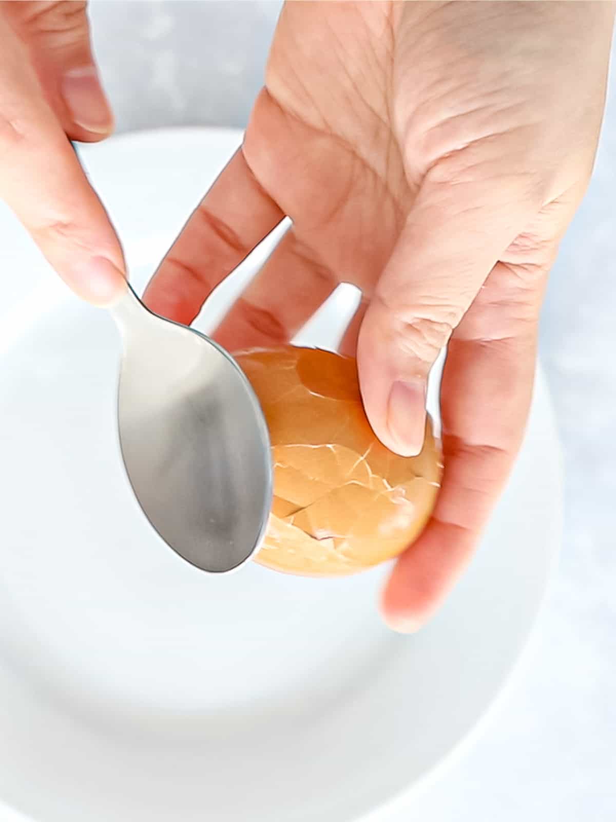 Tapping an egg shell with the back of a spoon to crack the shell.