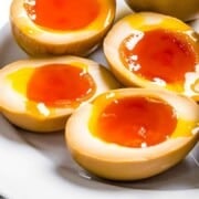 Ramen eggs or soy sauce eggs cut in half to reveal soft boiled eggs with runny jammy yolk.