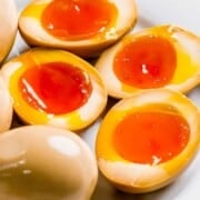 Soft boiled soy sauce eggs cut in half on a plate with text overlay.