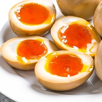 Ramen eggs marinated in soy sauce cut in half to reveal soft boiled eggs with runny yolks.