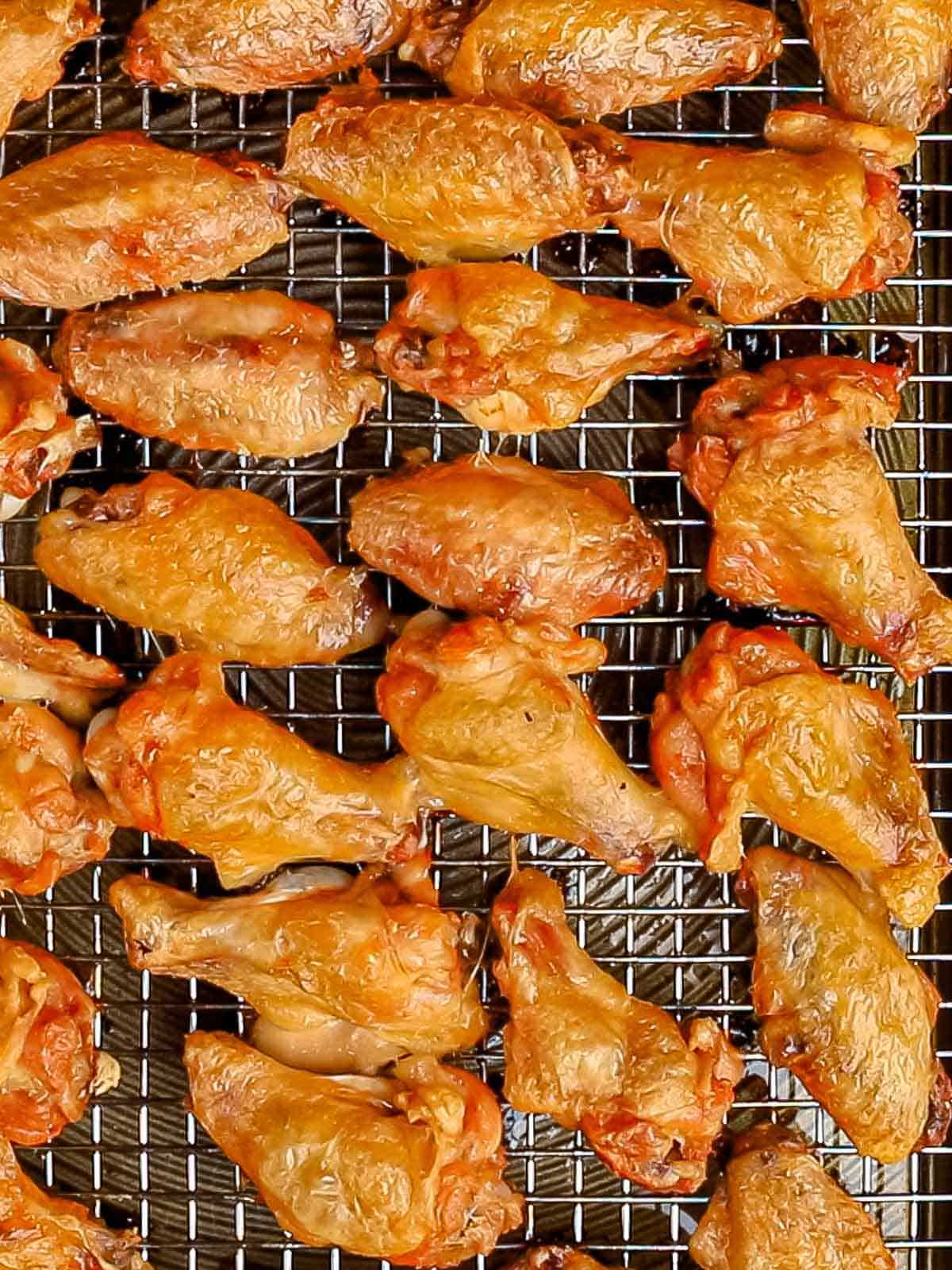 Crispy baked chicken wings with golden brown crispy skin on top of a wire rack.