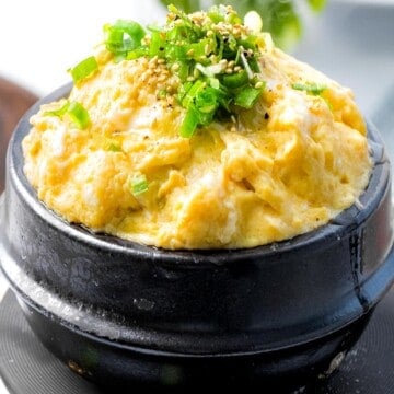 Korean steamed eggs garnished with scallions and sesame seeds.