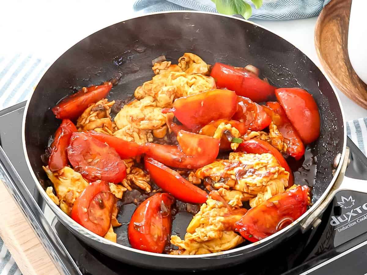 Tomatoes and eggs stir fried in a pan.