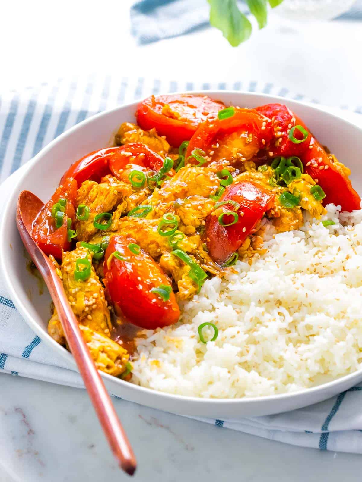 Chinese tomato egg stir fry with rice and spoon.