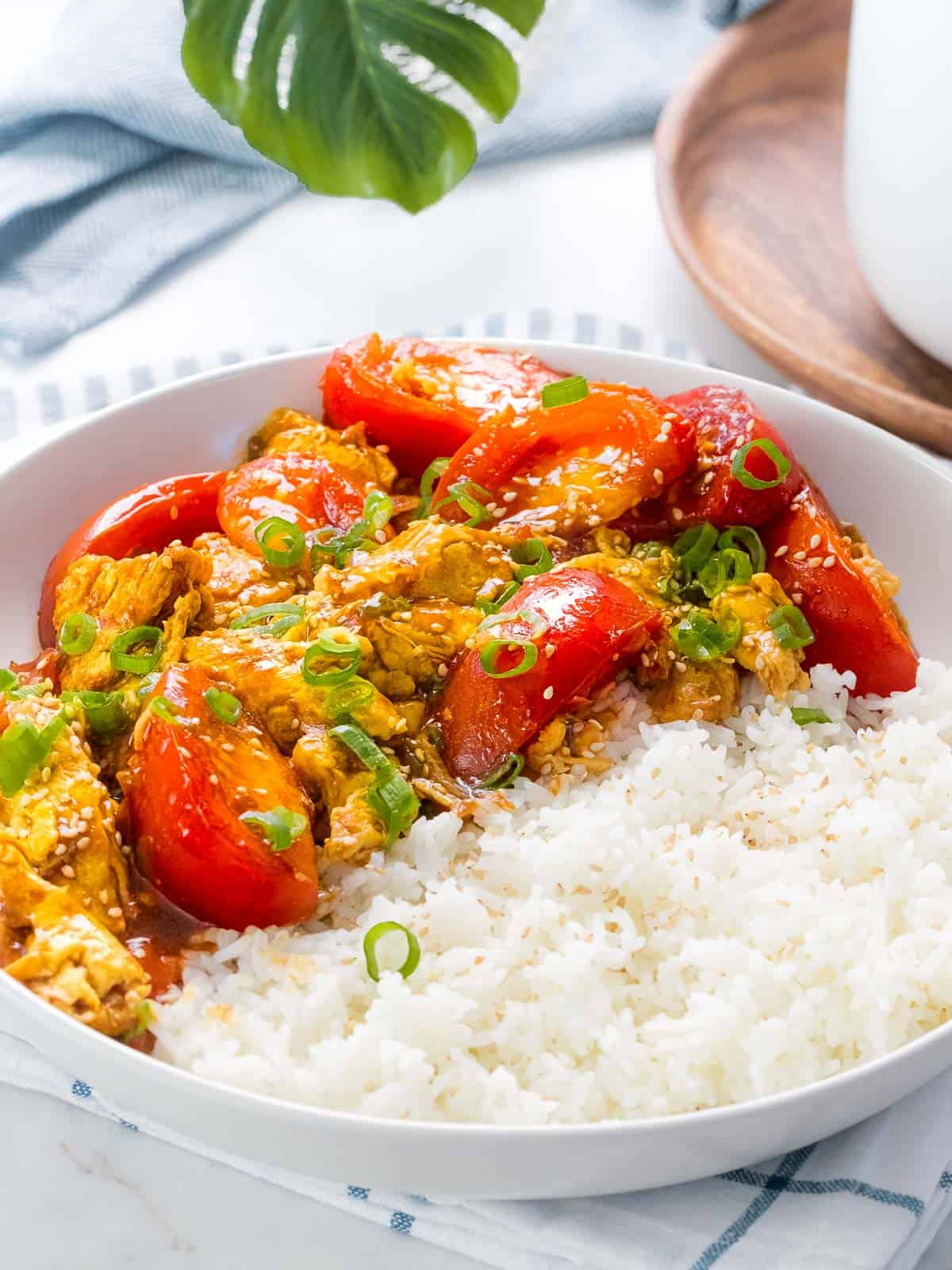 Chinese tomato egg stir fry served with rice and garnished with green onions.