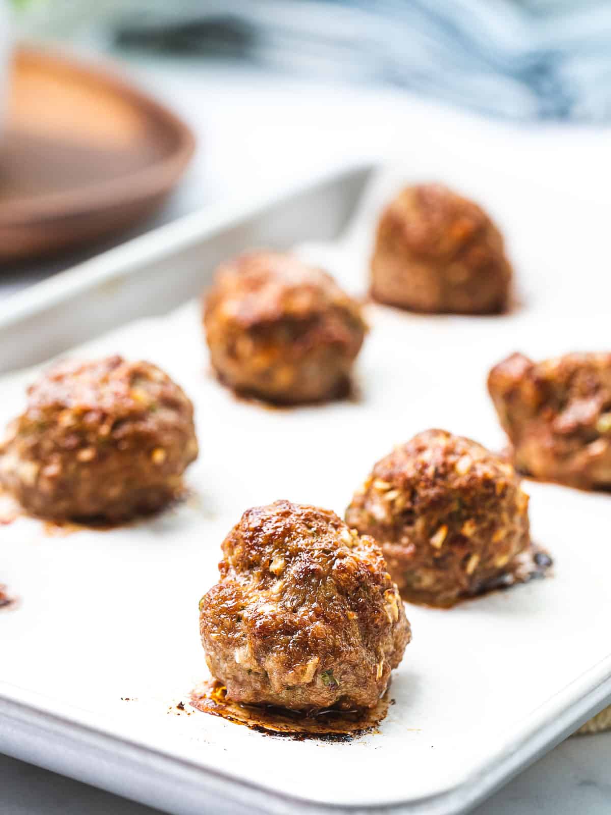 Baked Italian meatballs on a baking tray with a golden brown crust.