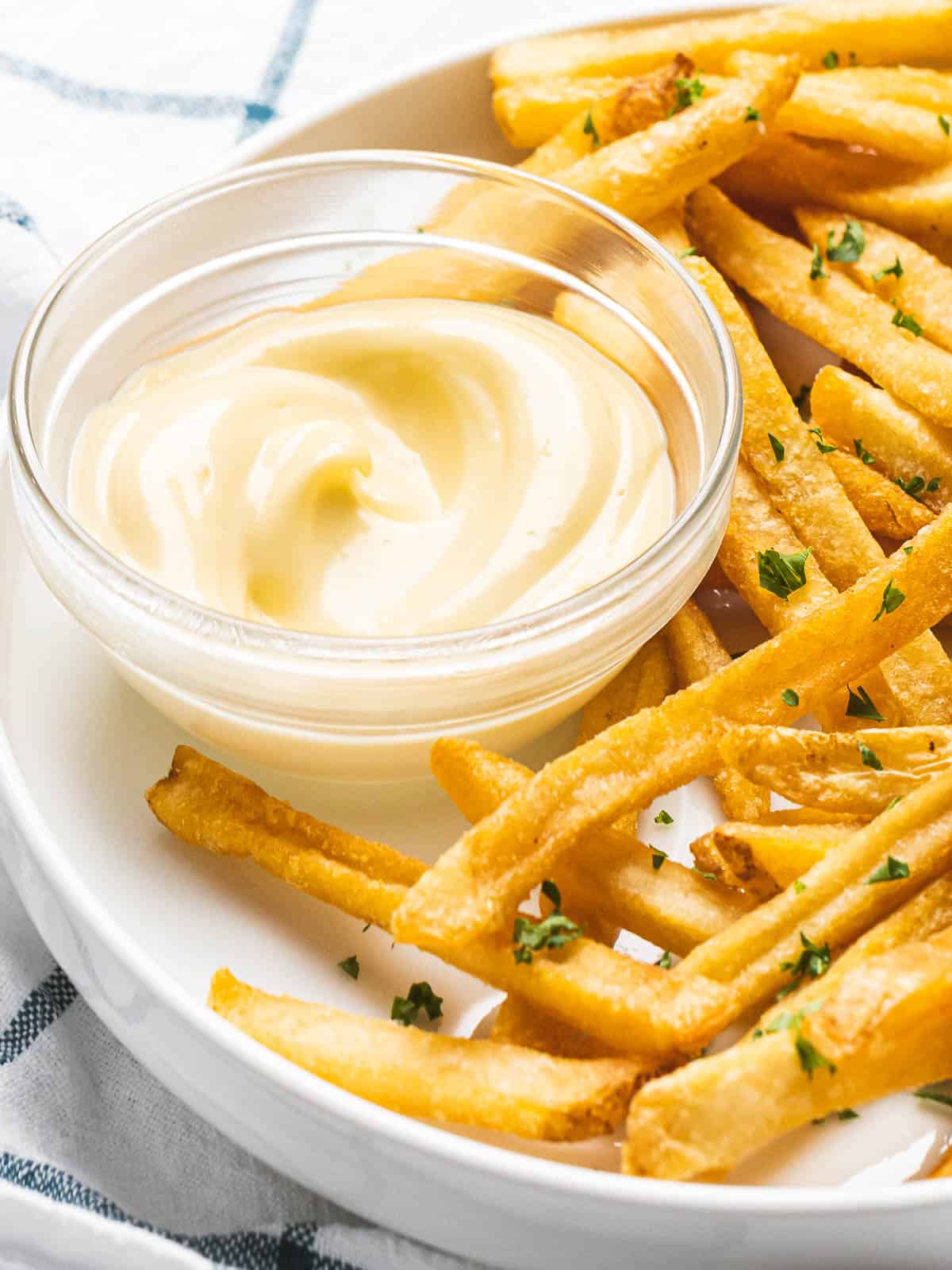 Easy garlic aioli sauce in a bowl next to French fries.