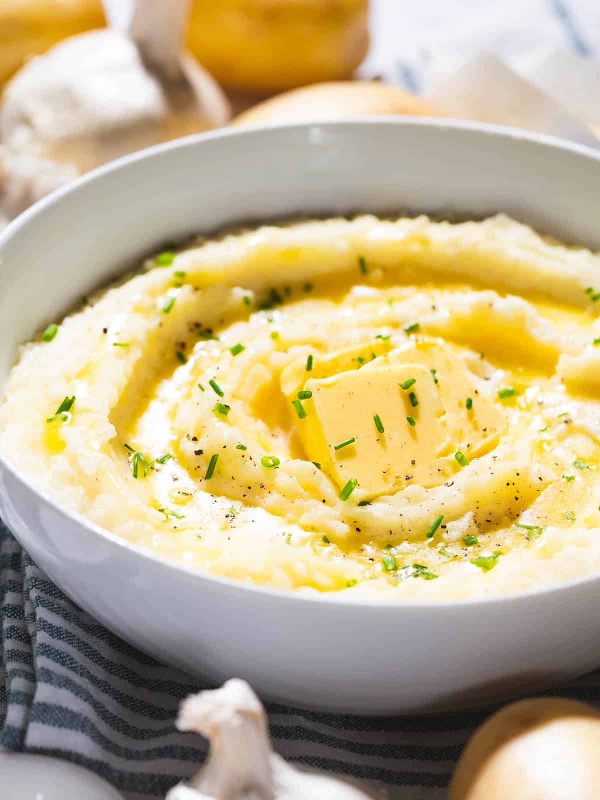 Garlic mashed potatoes with garlic butter and chives in a white bowl.