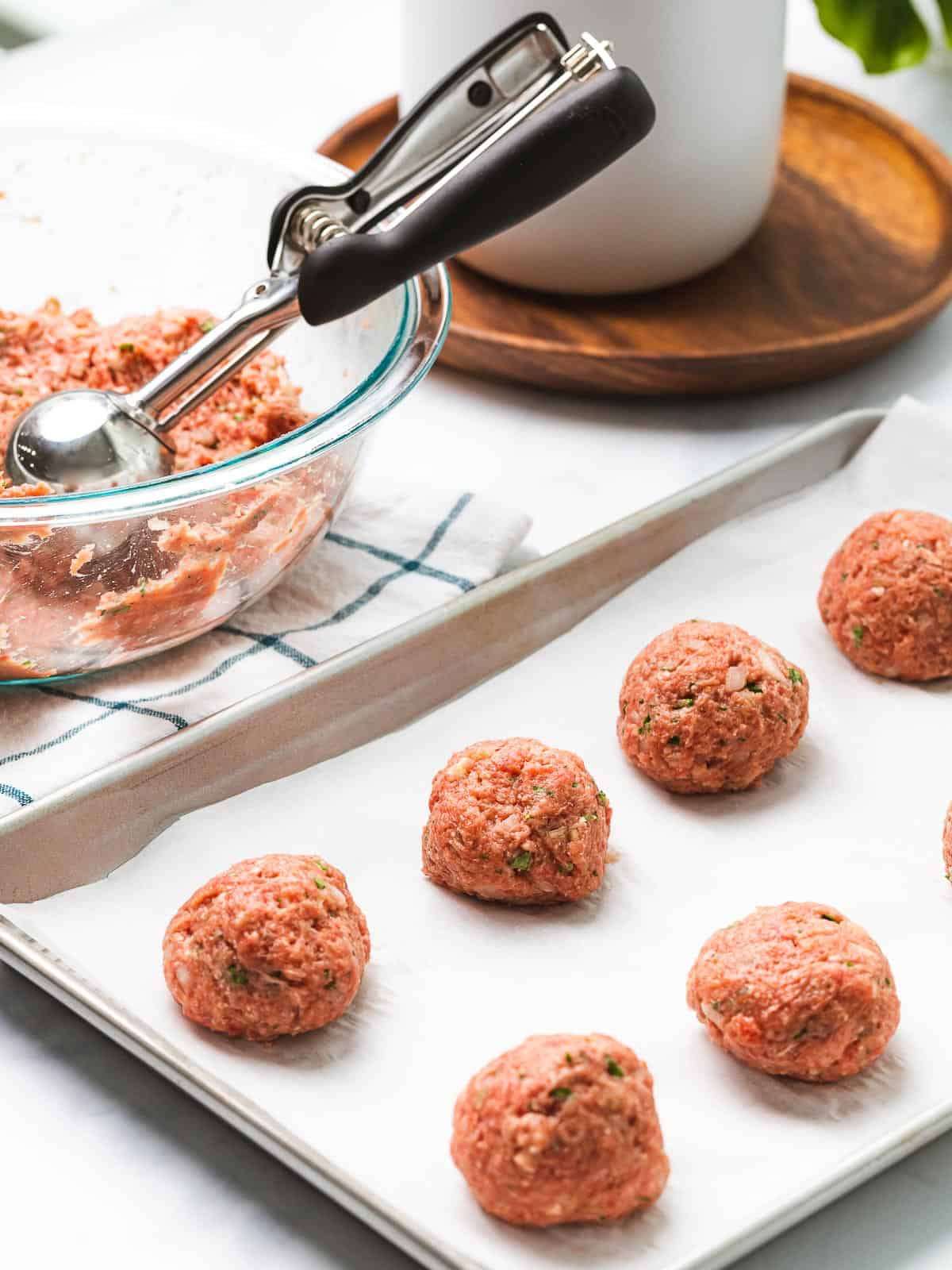 Uncooked meatballs formed on a baking tray.