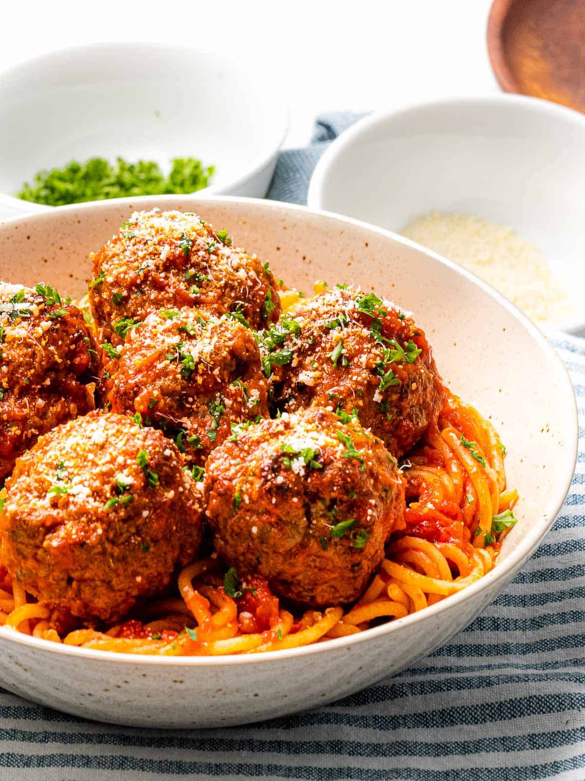 Tender and juicy Italian meatballs with a bowl of pasta.