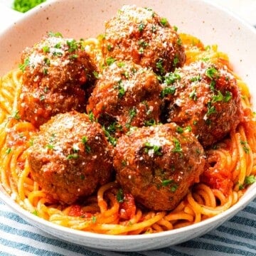 Italian meatballs with parmesan cheese on top of spaghetti.