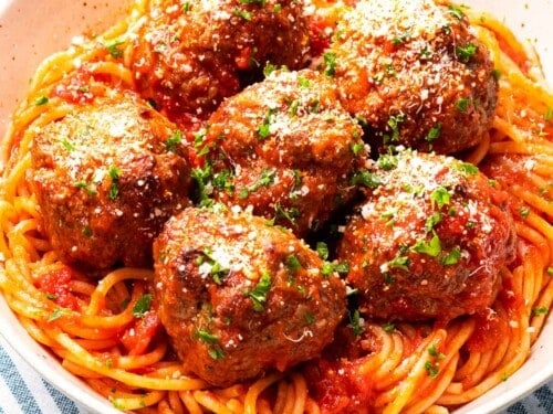 Italian meatballs with parmesan cheese on top of spaghetti.