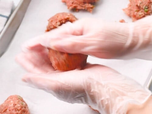 Rolling and shaping meatballs with hands.