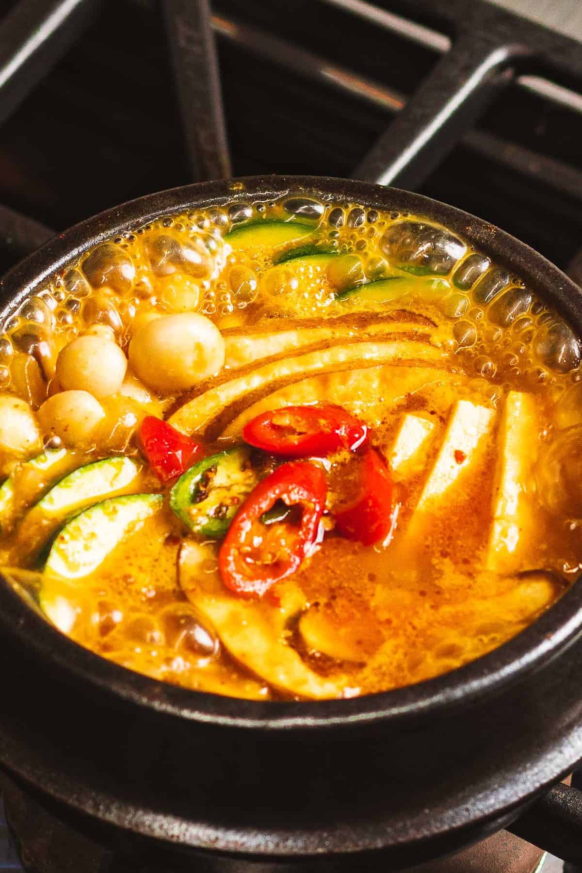 Doenjang jjigae with Korean soybean paste, vegetables, tofu, and peppers boiling in a pot.