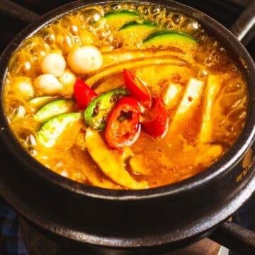 Doenjang jjigae with mushrooms, tofu, and peppers boiling in a pot.