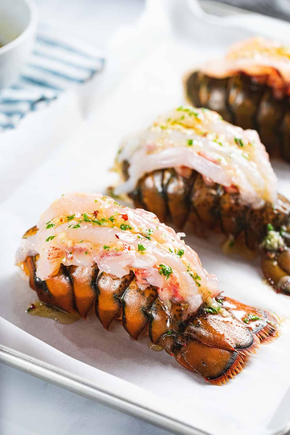 Raw lobster tail butterflied with garlic butter on top.