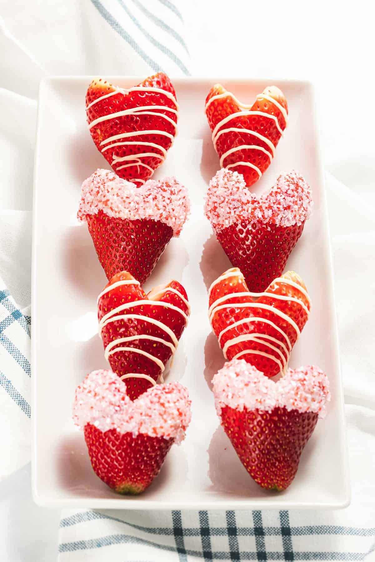 Strawberry hearts decorated with white chocolate and sprinkles.