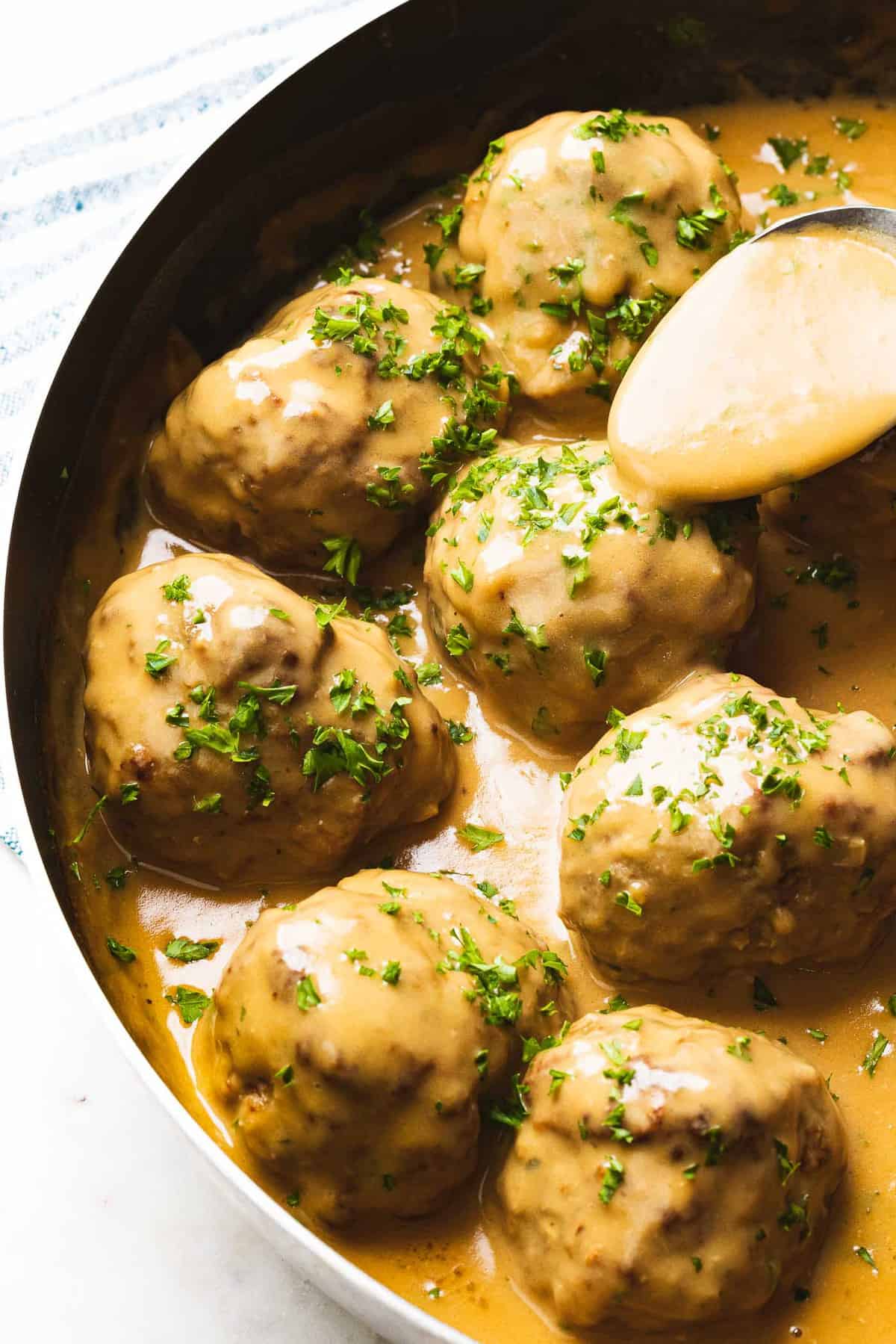 Swedish meatballs with gravy poured on top by spoon.