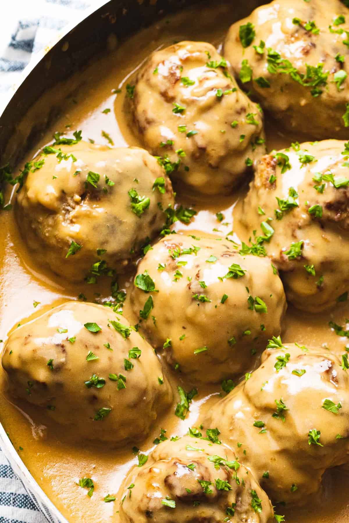 Swedish meatballs in sauce with garnish of chopped parsley.