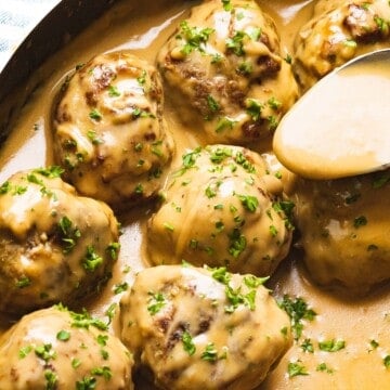Swedish meatballs with sauce being spooned on top.