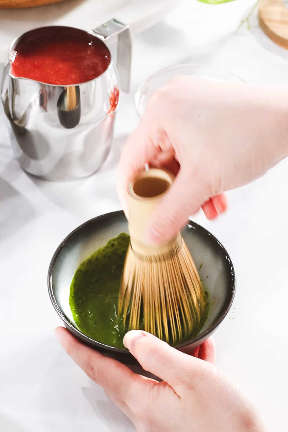 Matcha powder mixed with a bamboo matcha whisk in a bowl.