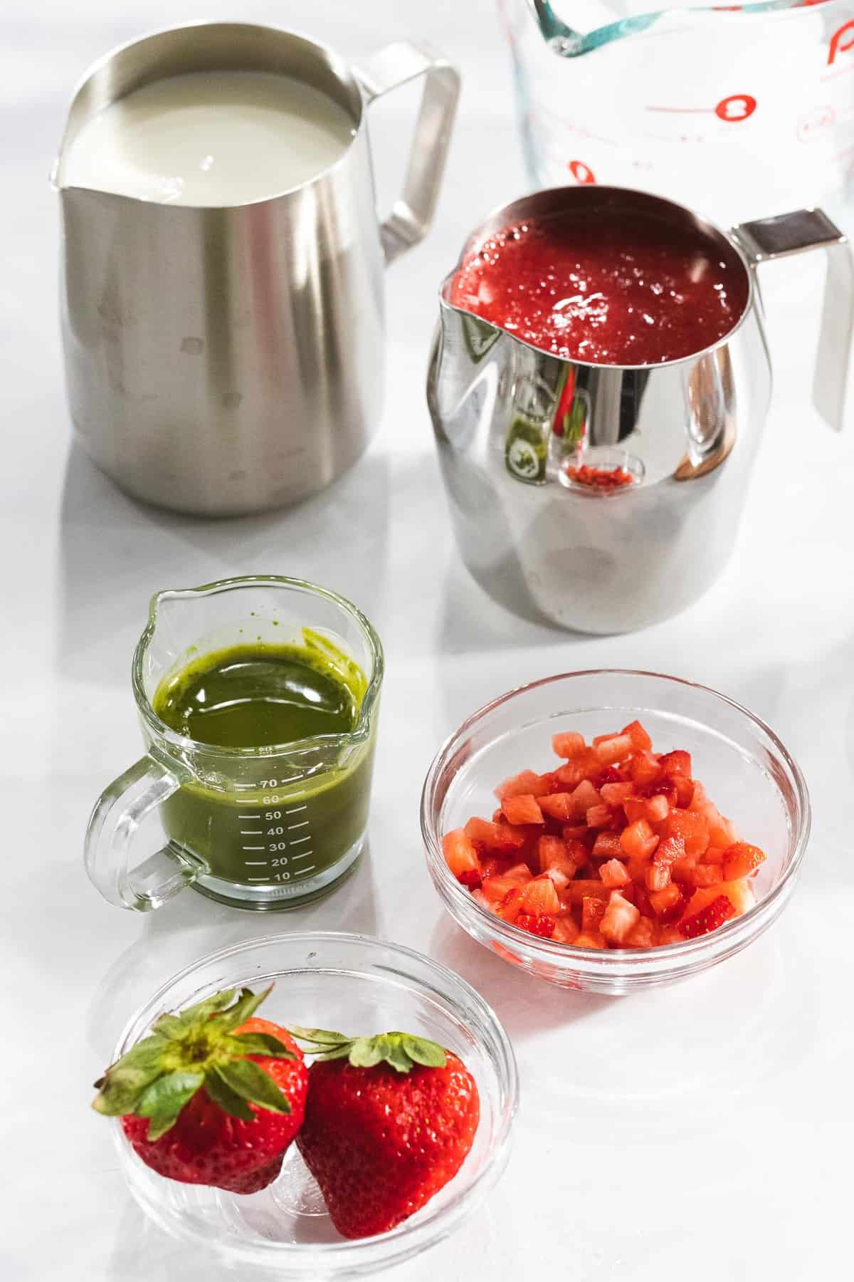 Ingredients for making strawberry matcha latte including green matcha and strawberry puree.