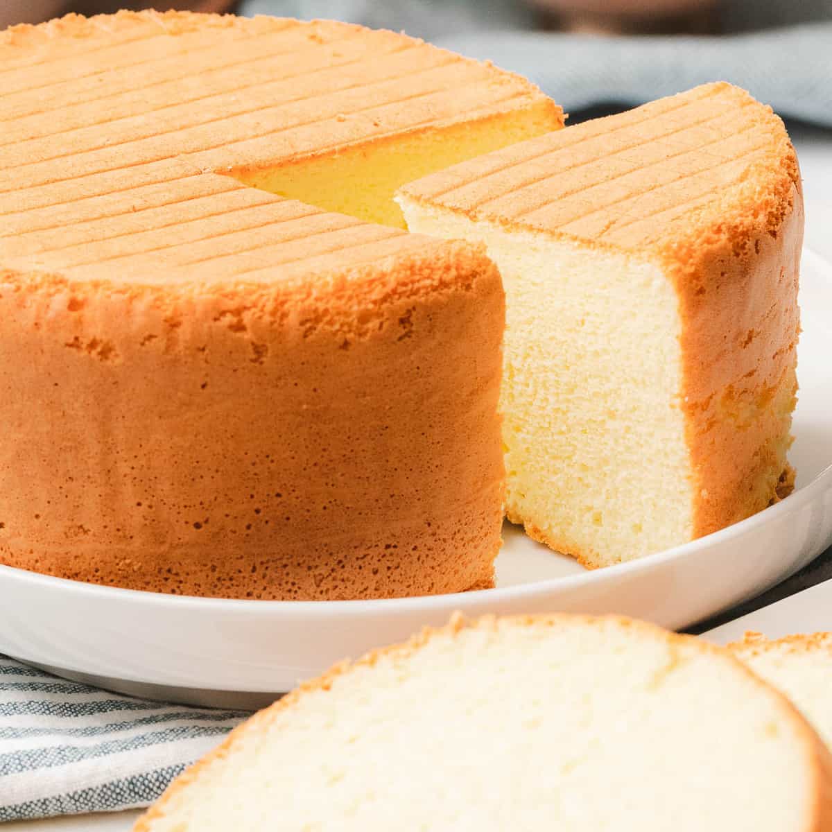 Easy sponge cake with slice taken out to reveal soft, fluffy, texture.