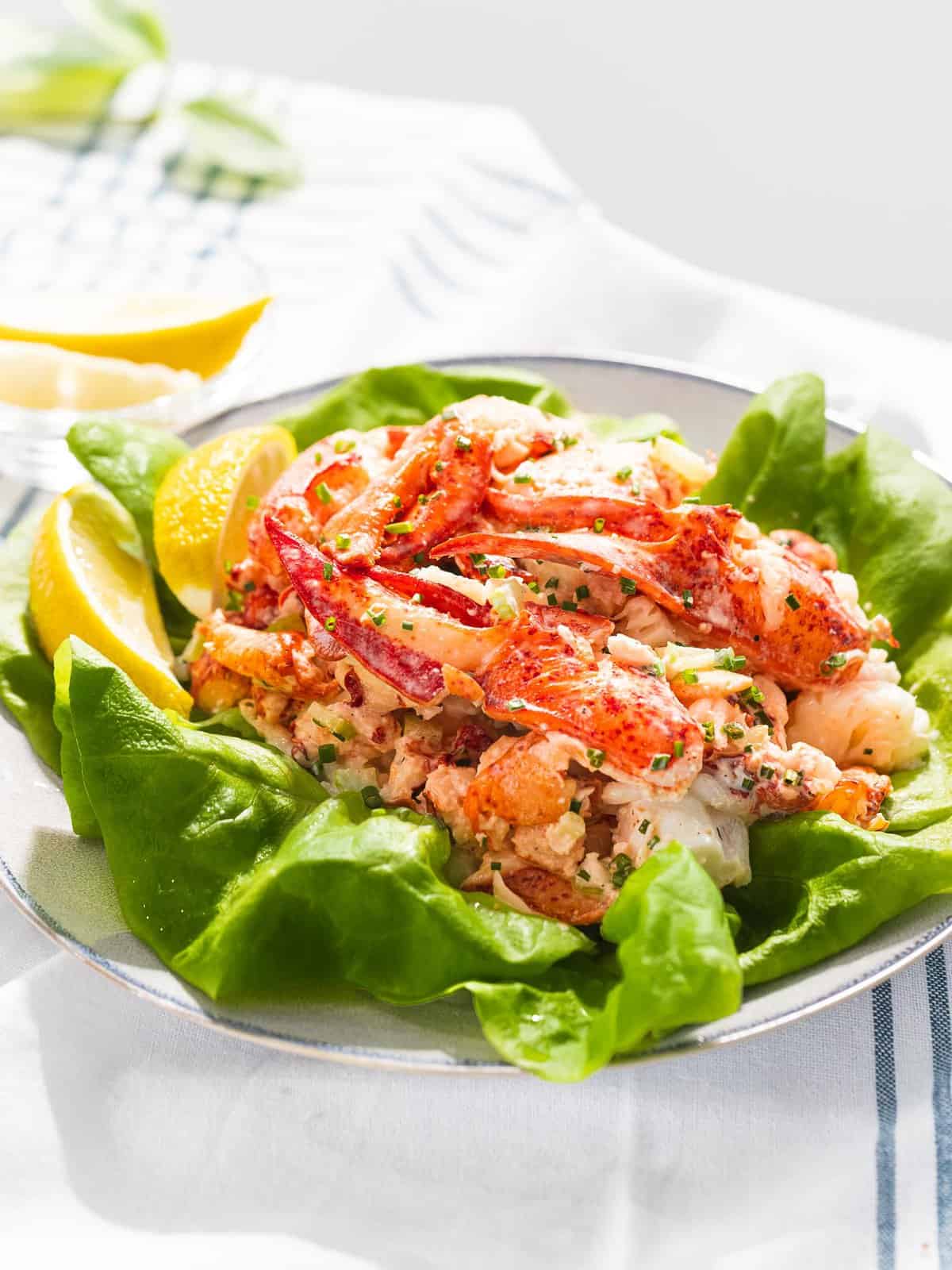 Lobster salad on top of lettuce next to lemons.