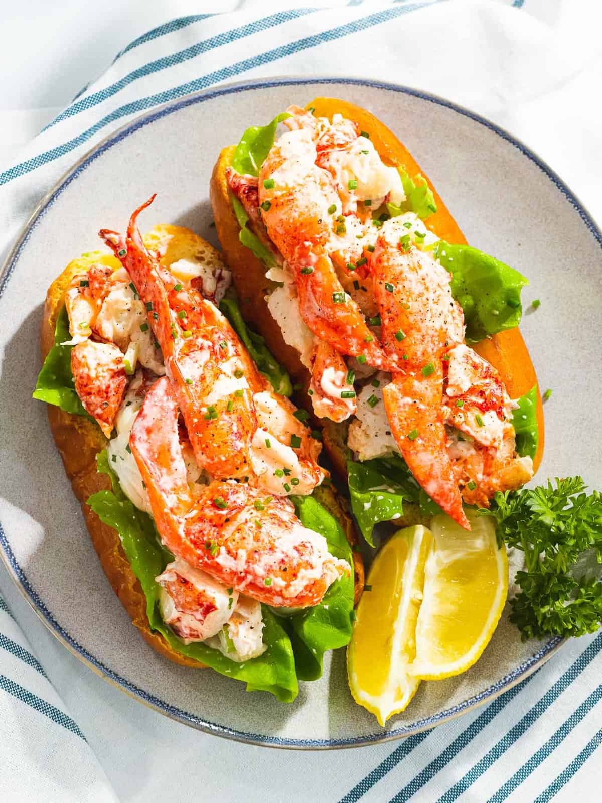 Maine lobster rolls on a plate next to lemons.