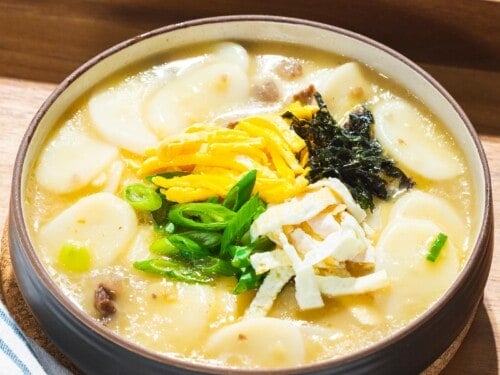 Tteokguk or Korean rice cake soup in a beef broth garnished with eggs, seaweed, and green onions.
